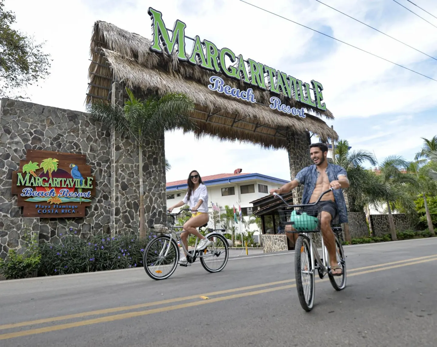 Cyclists ride under the entrance sign at Margaritaville Beach Resort Playa Flamingo.
