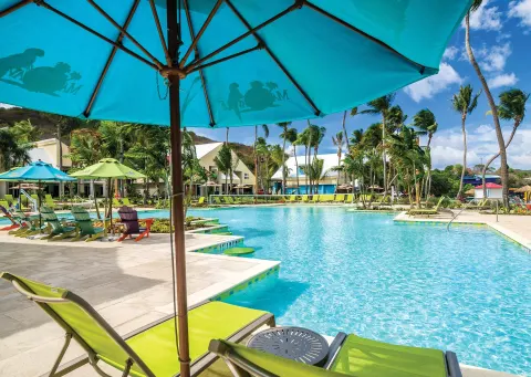 Pool deck with turquoise umbrella and loungers at Margaritaville Vacation Club - St. Thomas.