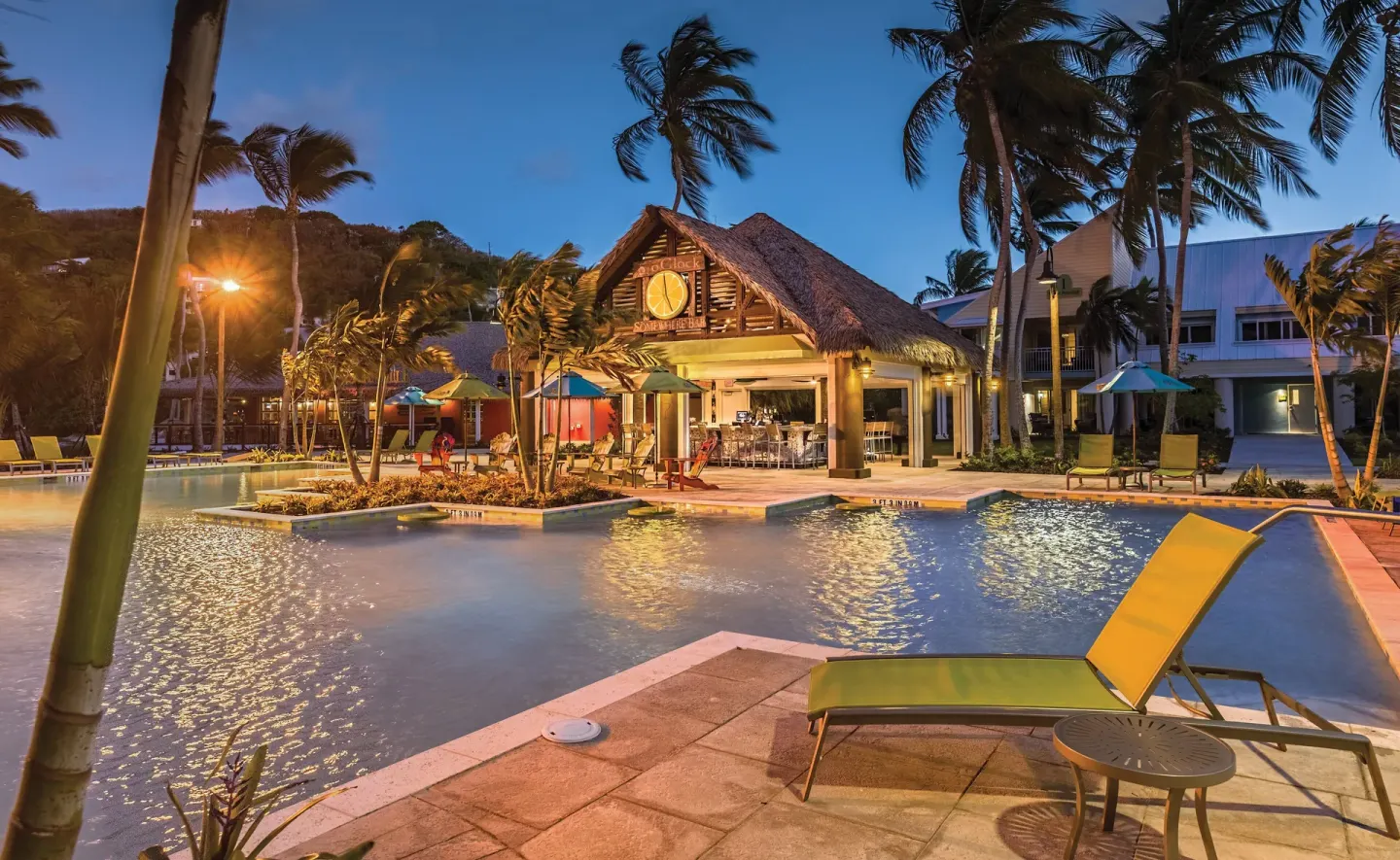 Resort pool and thatched poolside bar at dusk at Margaritaville Vacation Club - St. Thomas.