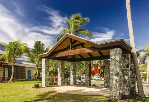 Stone entry pavilion and lawn with palm trees at Margaritaville Vacation Club - St. Thomas.