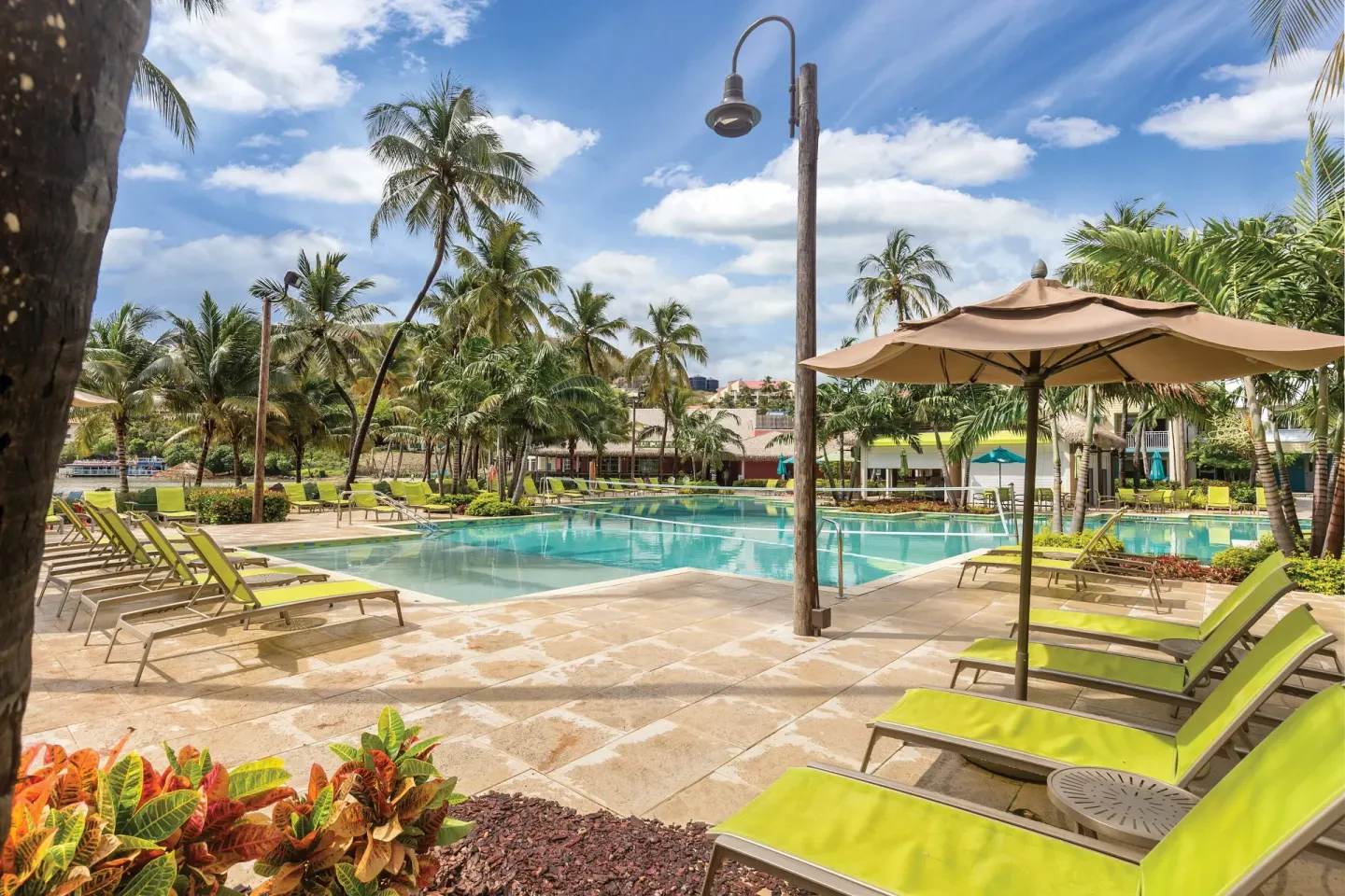 Sunny pool deck with umbrellas, loungers, and palms at Margaritaville Vacation Club - St. Thomas.