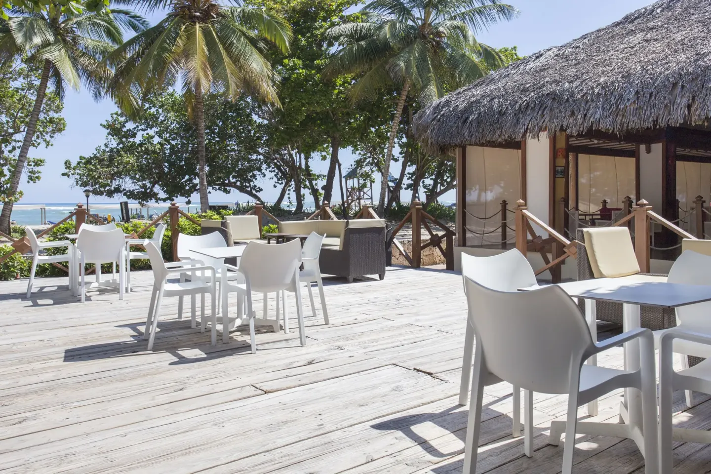 Outdoor deck with white tables near the beach at Marien Puerto Plata.