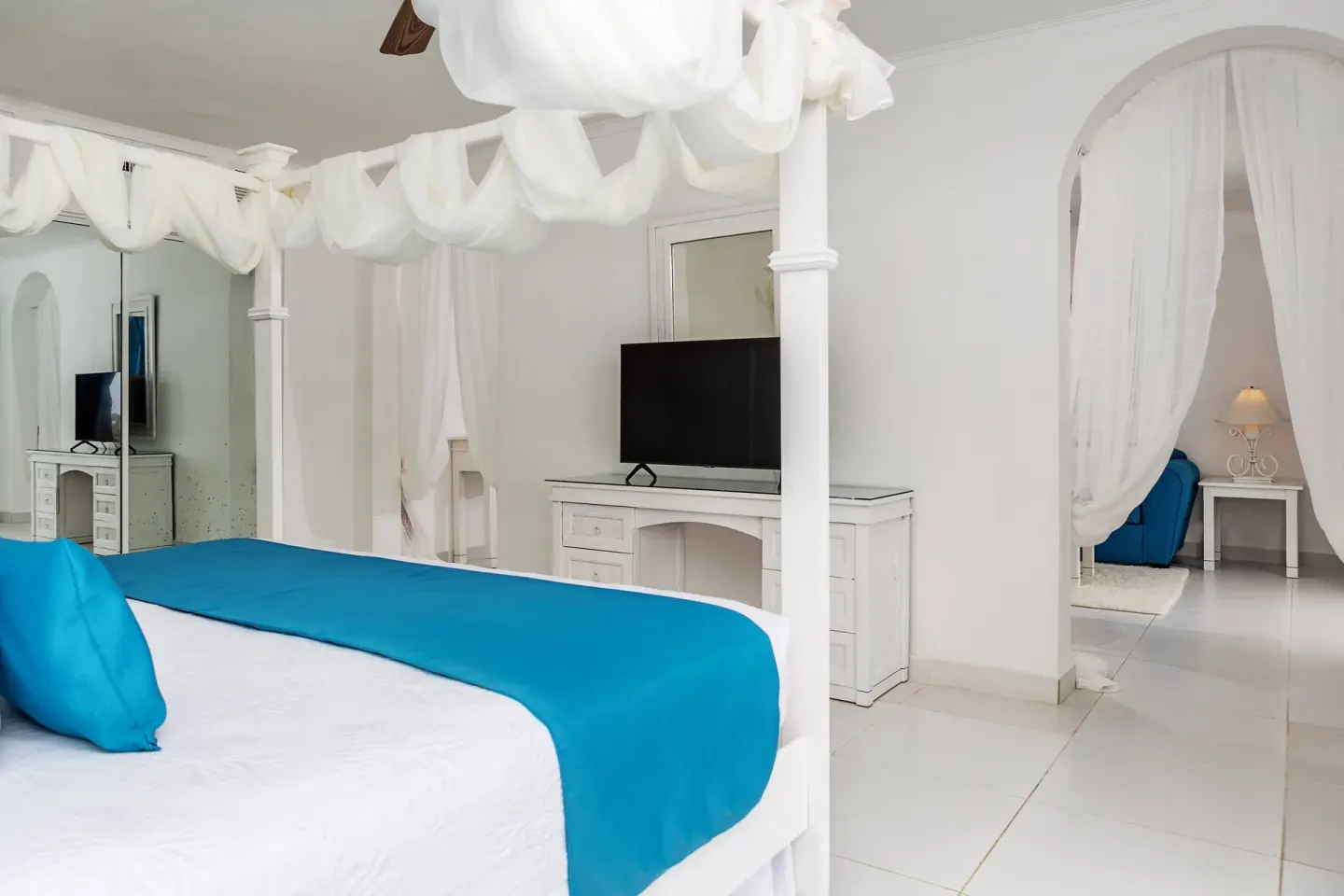 White canopy king bed and sitting area in a guest room at Marien Puerto Plata.