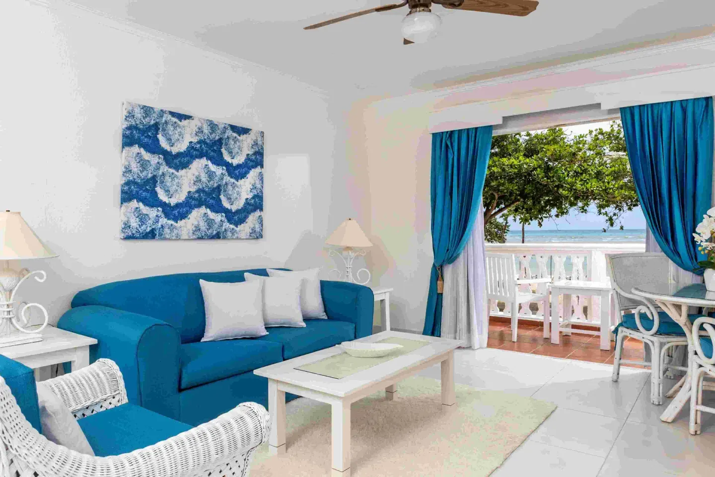 Guest room living area with blue sofa and ocean-view balcony at Marien Puerto Plata.