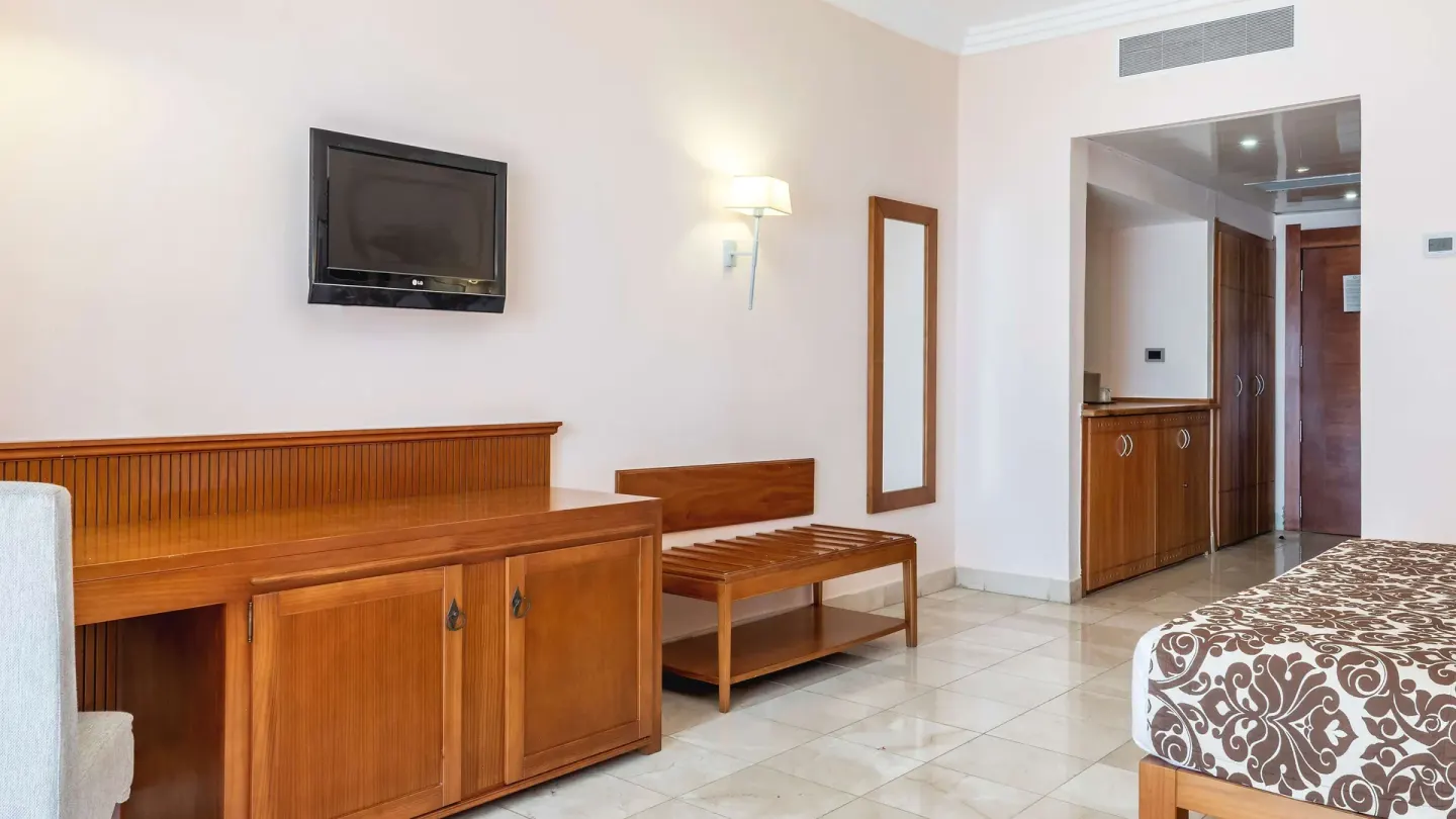 Guest room with patterned bed, TV cabinet and luggage bench at Marien Puerto Plata.