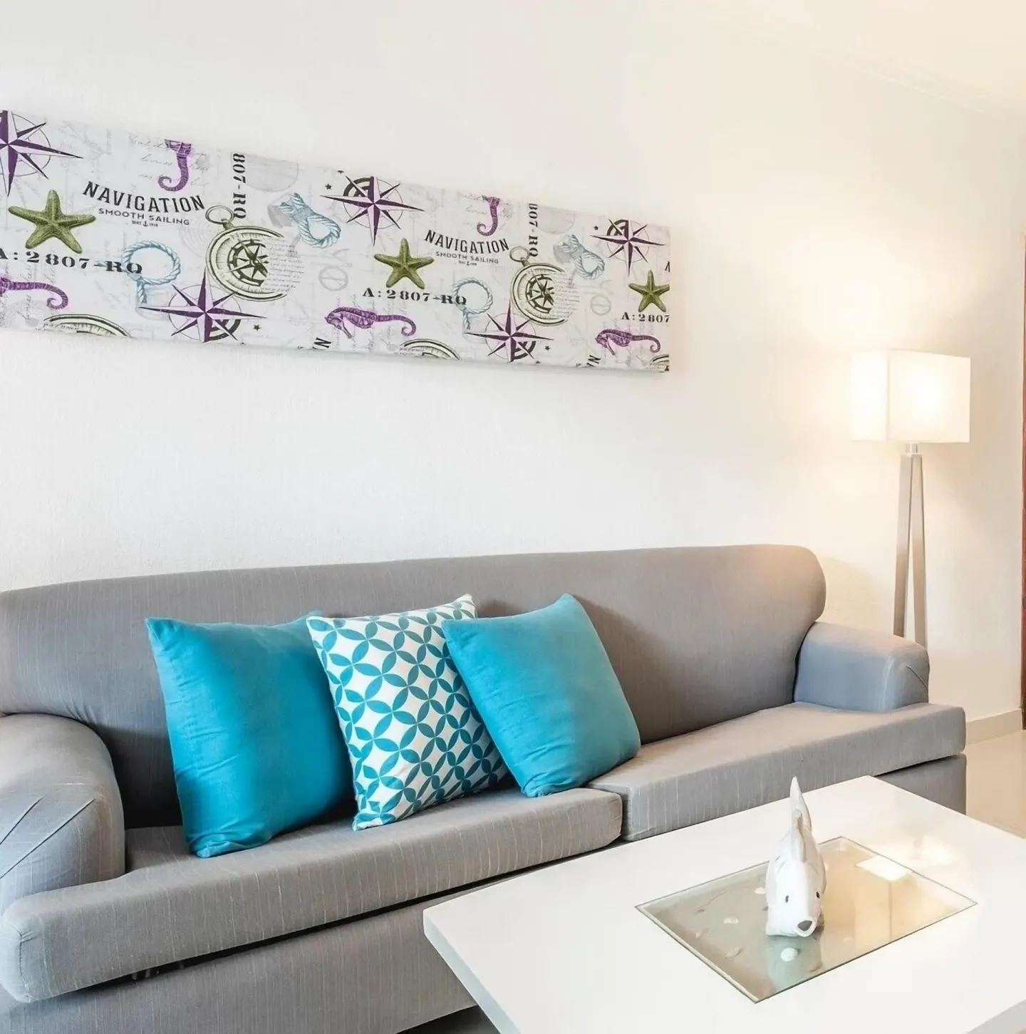 Guest room sitting area with gray sofa and nautical wall art at Marien Puerto Plata.