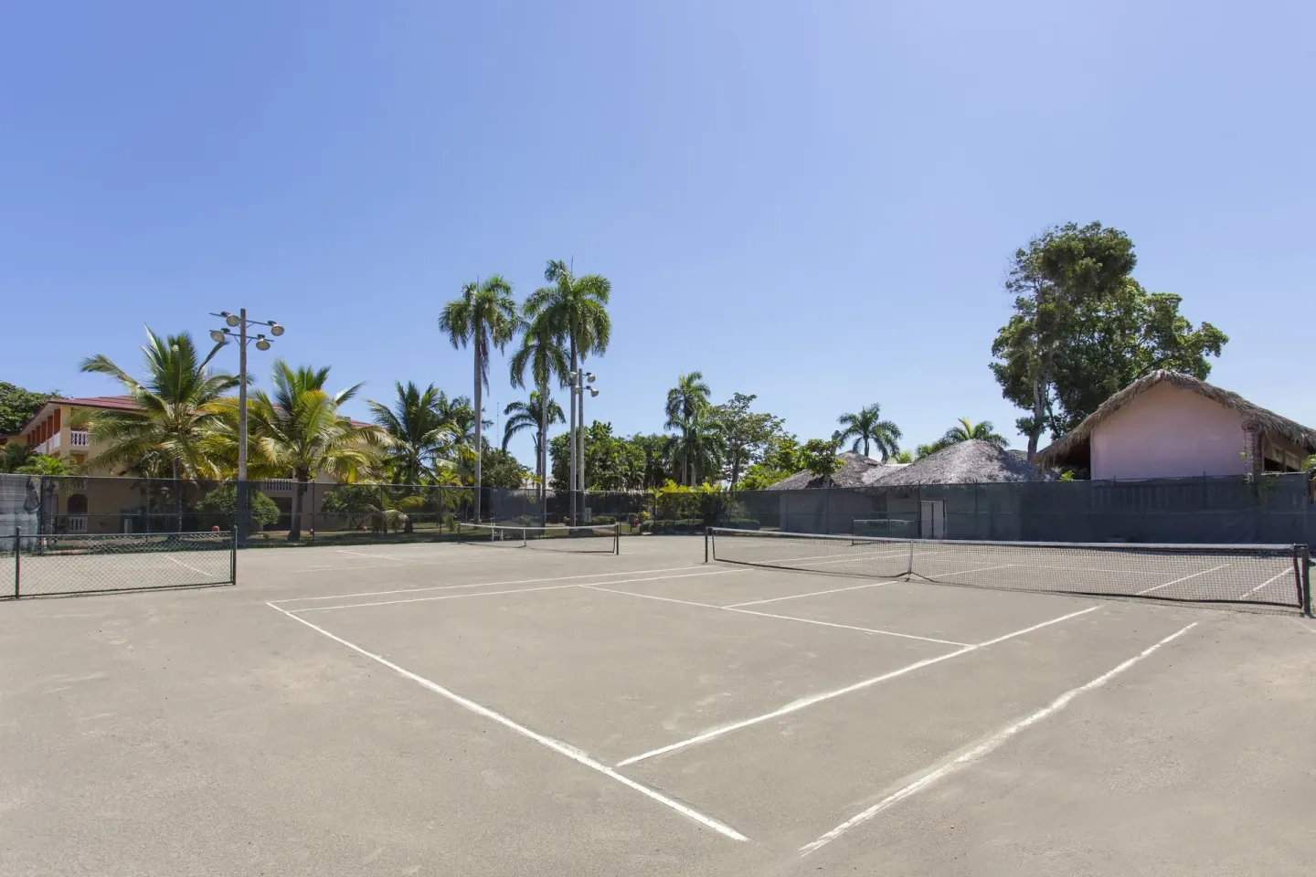 Outdoor tennis courts bordered by palms and resort buildings at Marien Puerto Plata.