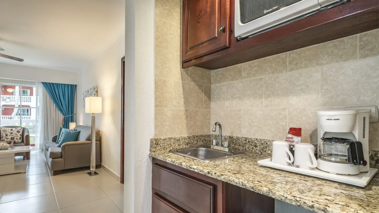 Suite kitchenette with sink, coffeemaker, mugs, and blue-accent living area at Marien Puerto Plata.