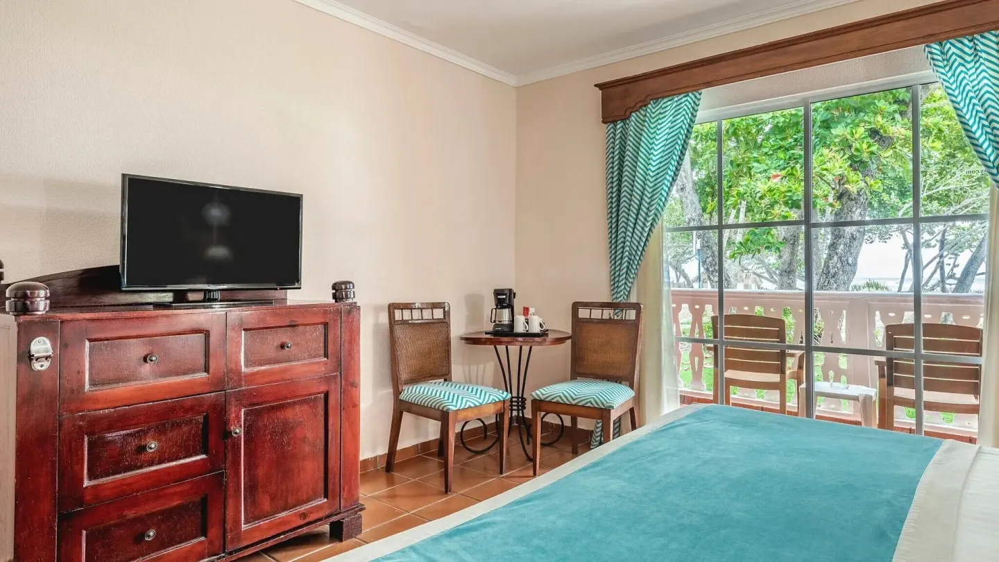 Deluxe Ocean View room with TV cabinet, coffee table, bed, and balcony at Marien Puerto Plata.