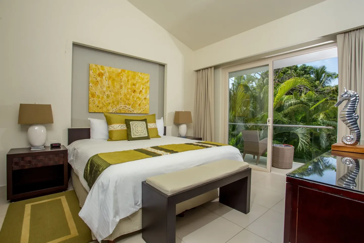 King bed guest room with balcony and palms at Marival Distinct World Spa.
