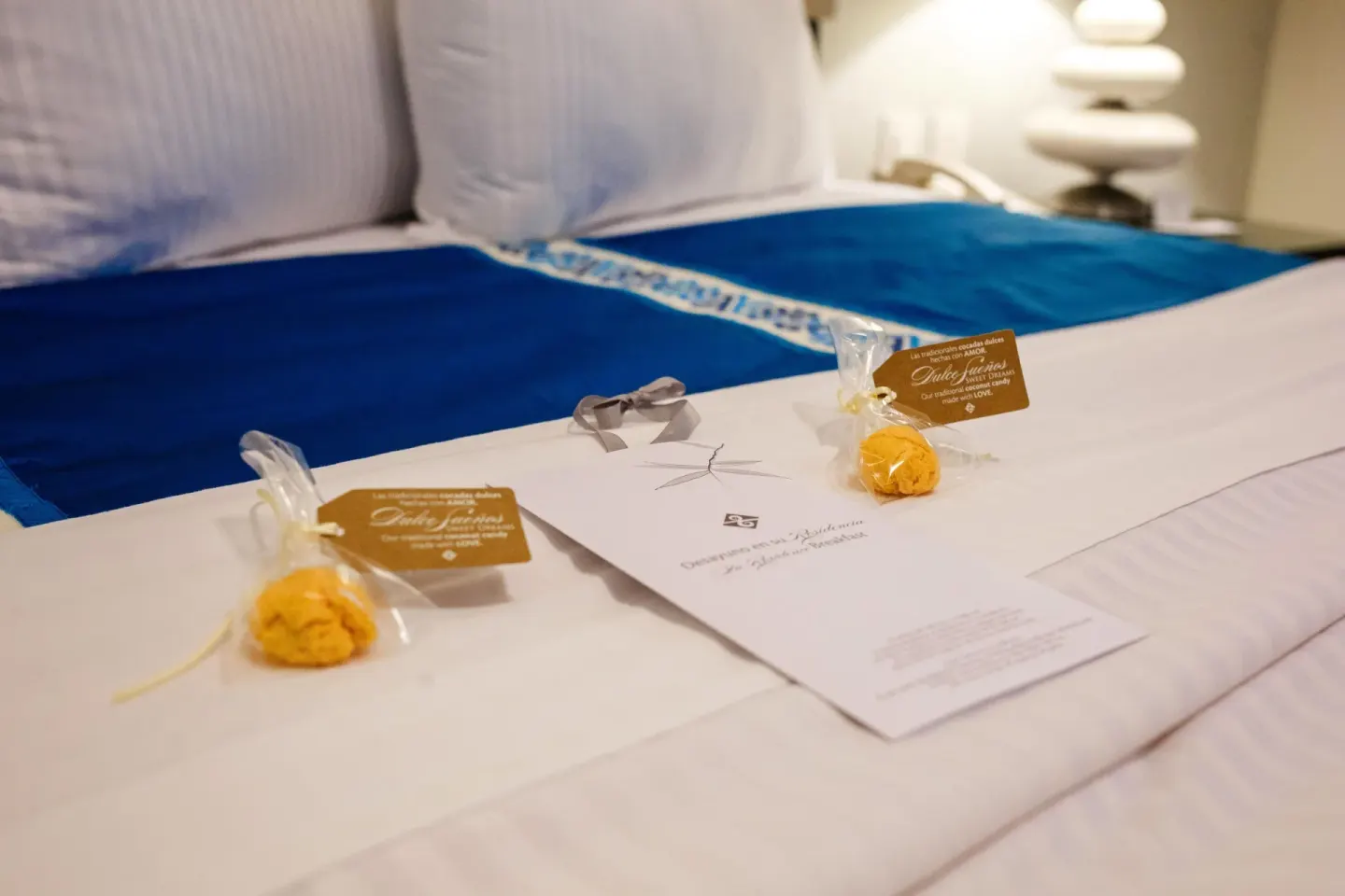 Bed with blue accents, welcome treats, and a note at Marival Distinct World Spa.