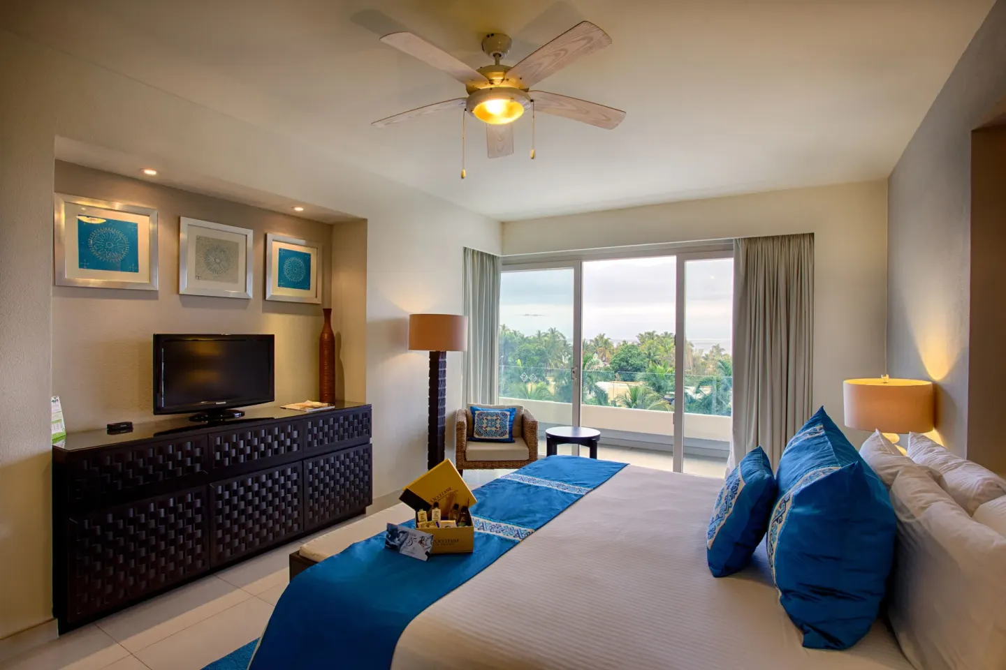 Guest room with a king bed, dresser, TV, and balcony view at Marival Distinct World Spa.