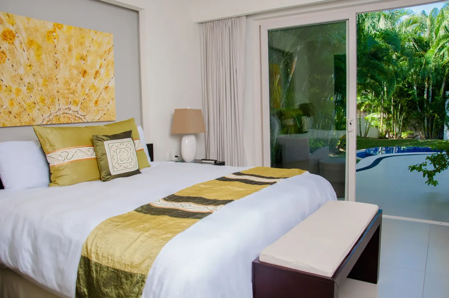 King bed beside glass doors facing palms and a small pool at Marival Distinct World Spa.