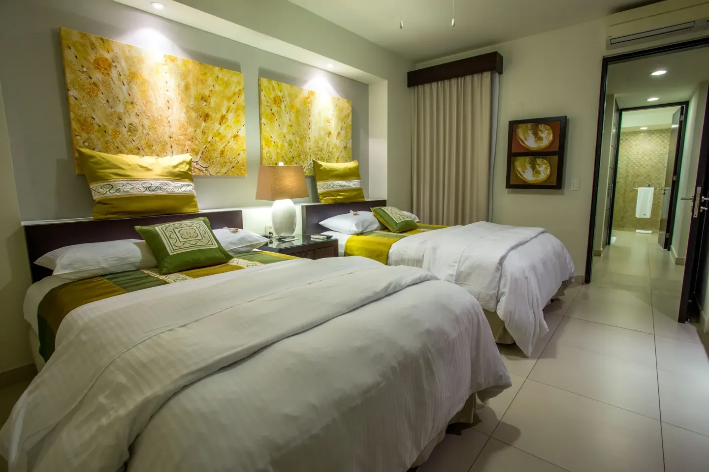 Two double beds with gold accents in a guest room at Marival Distinct World Spa.