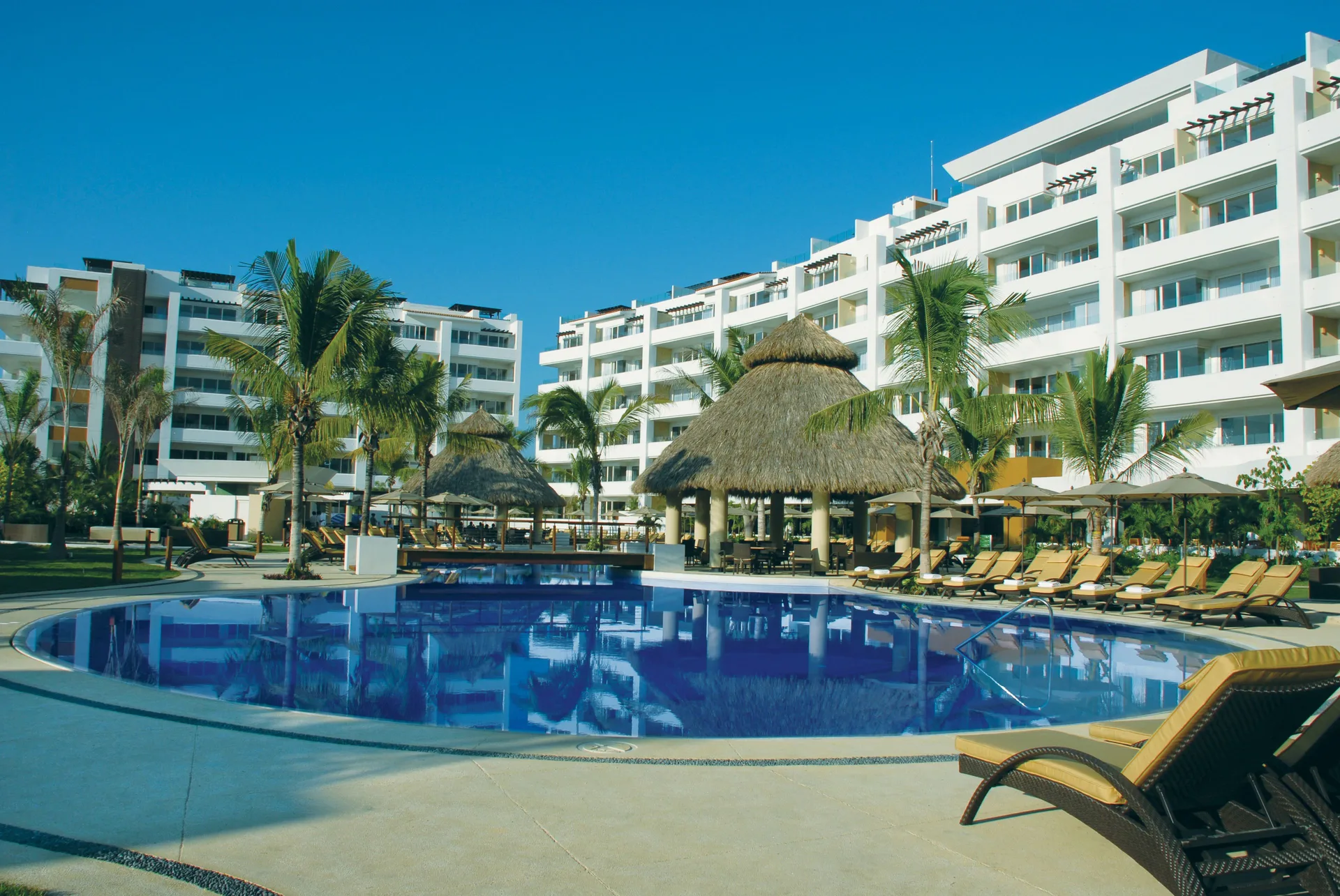 Main pool with palapa seating and resort buildings at Marival Distinct World Spa.