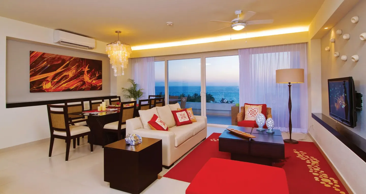 Ocean-view suite living and dining room with red accents at Marival Distinct World Spa.