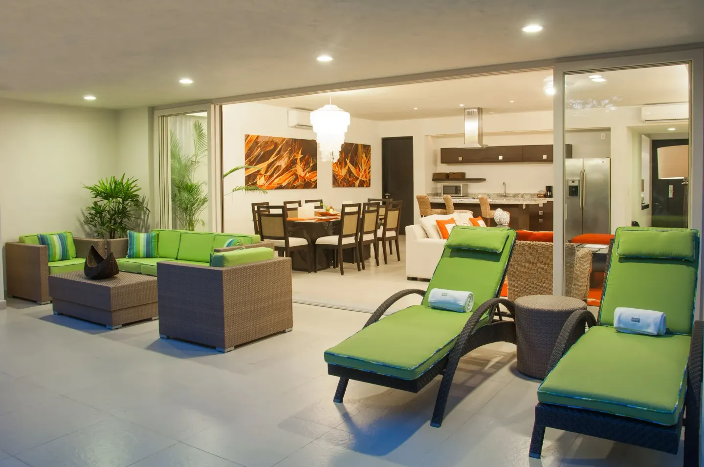 Patio lounge with green loungers beside an open living and kitchen area at Marival Distinct World Spa.