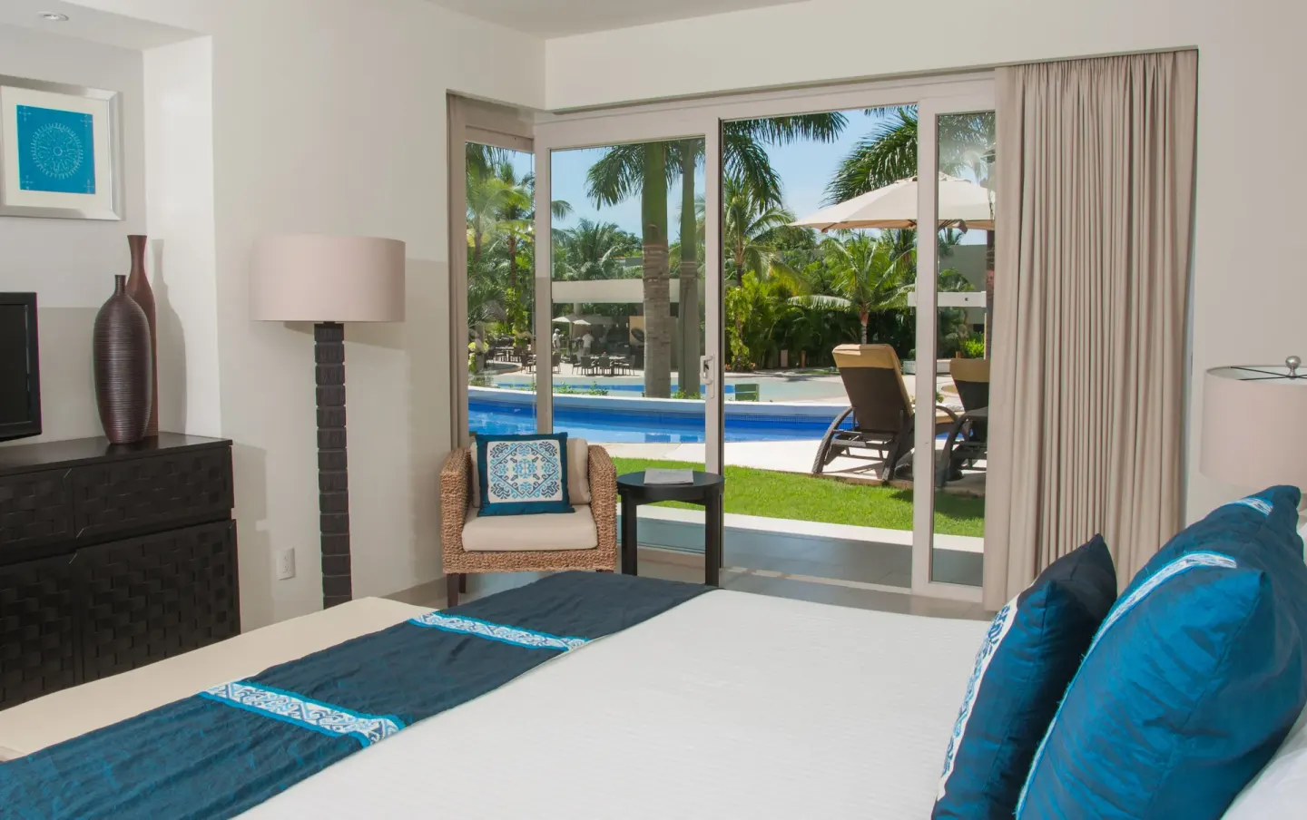 Guest room with a king bed opening to a poolside patio at Marival Distinct World Spa.