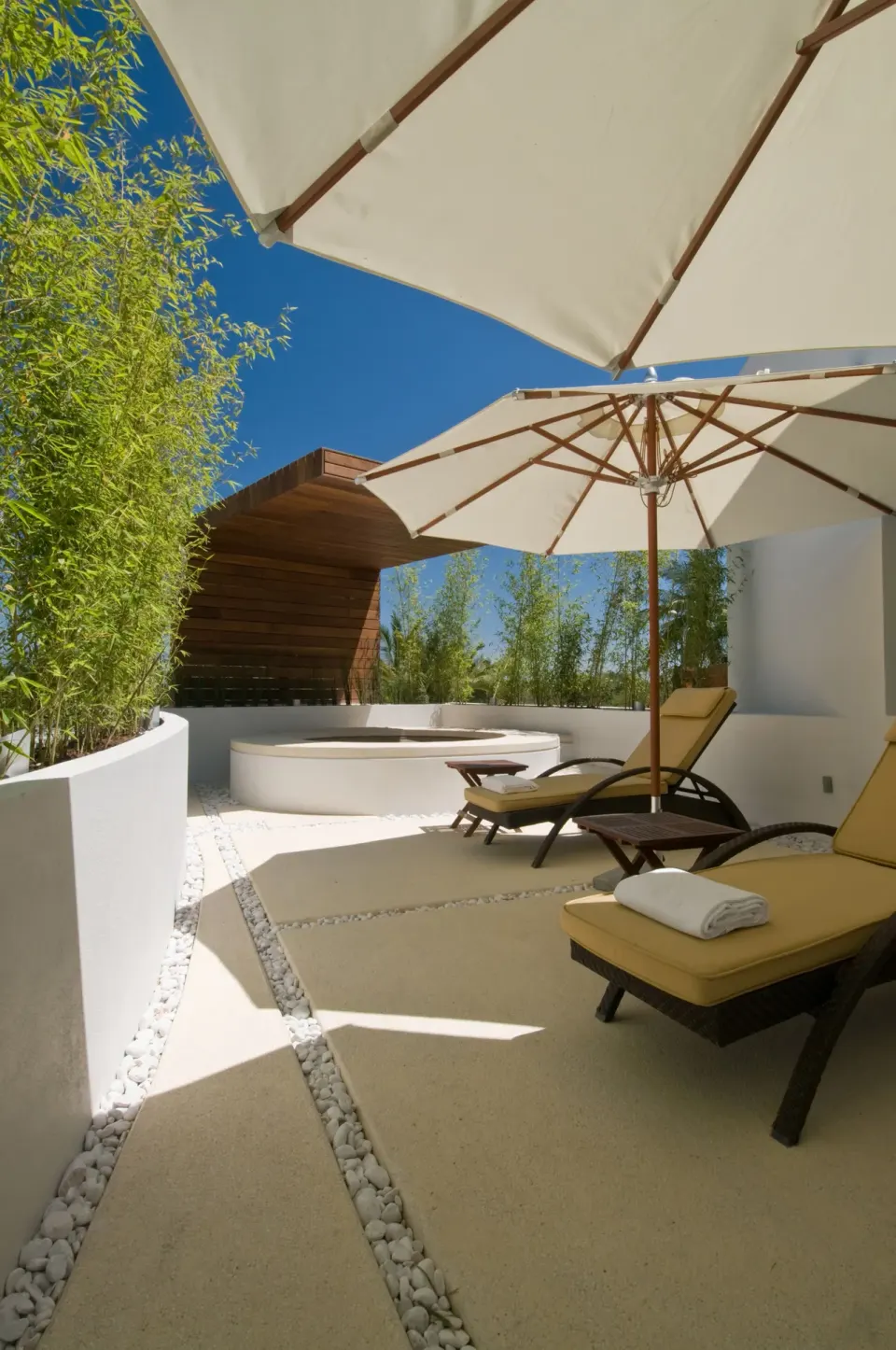 Private terrace with loungers, umbrellas, and plunge tub at Marival Distinct World Spa.