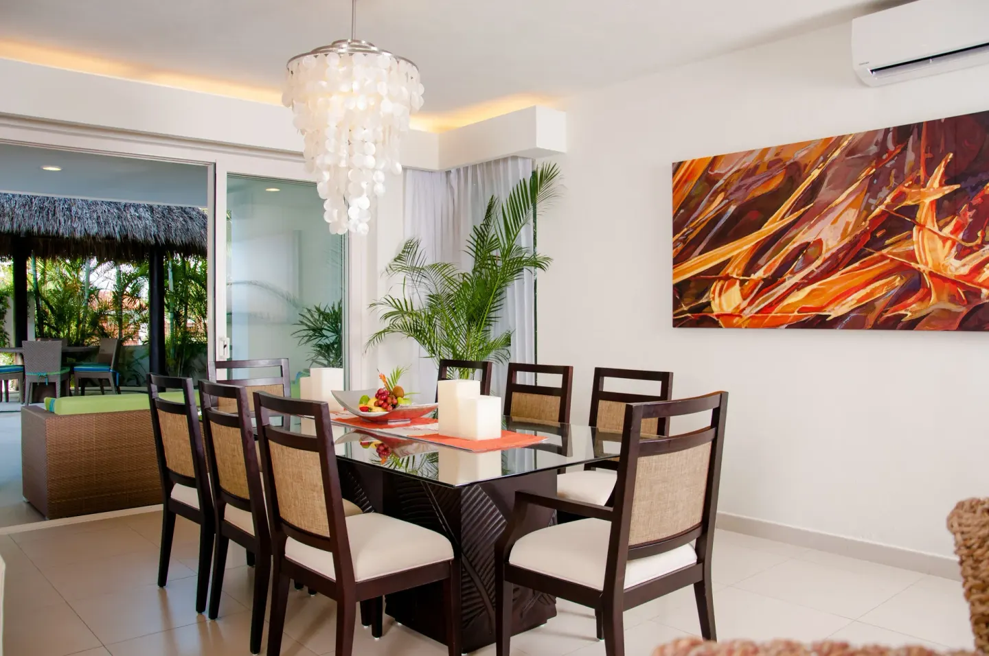 Suite dining area with glass table, shell chandelier, and terrace access at Marival Distinct World Spa.