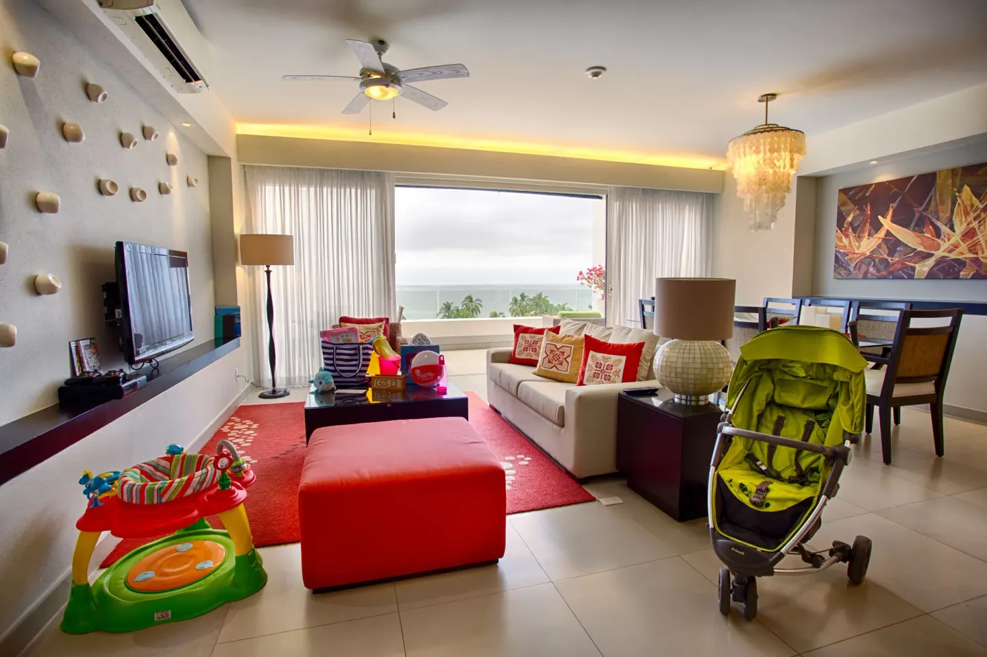 Living room with ocean view, sofa, dining area, and children's items at Marival Distinct World Spa.
