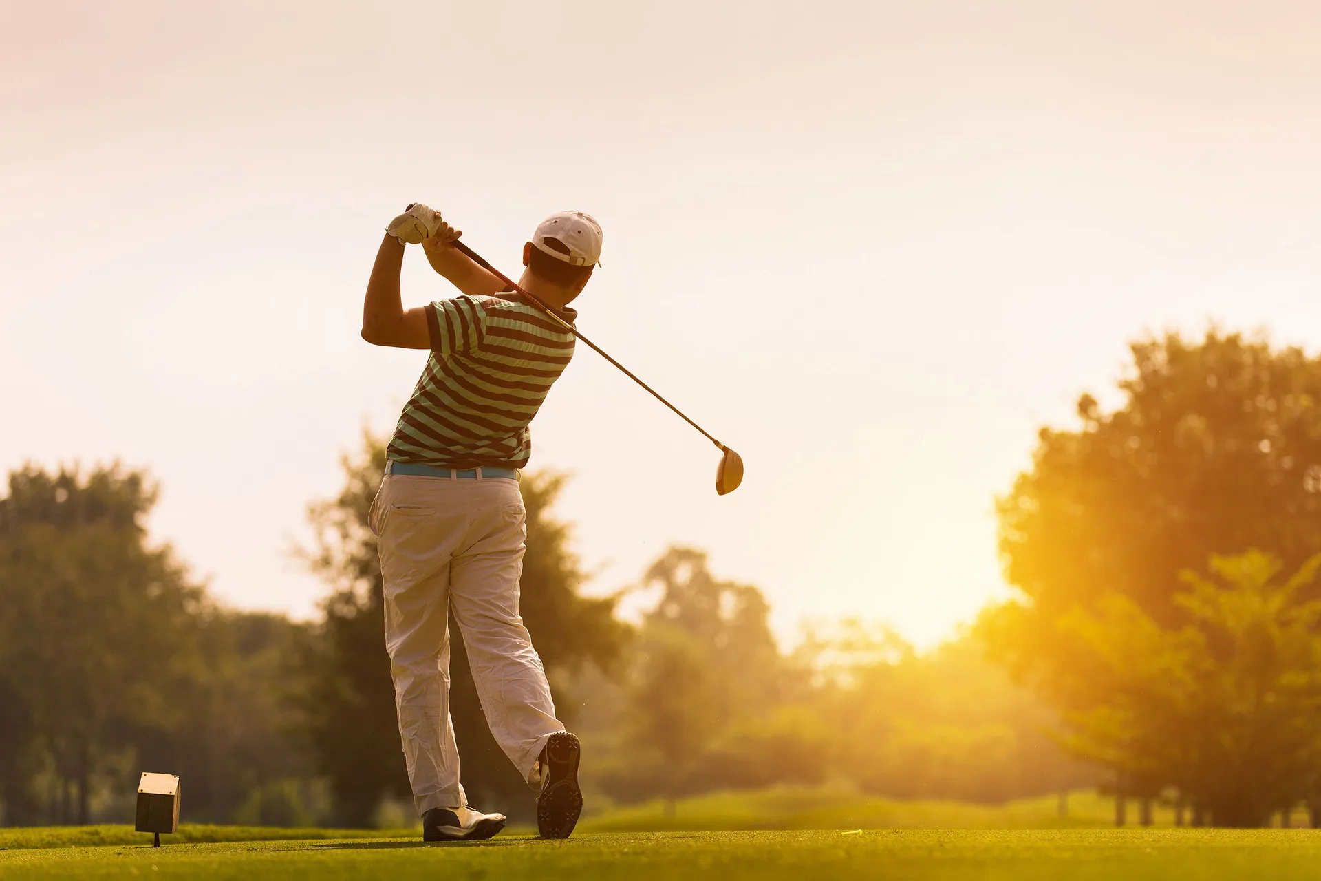 Golfer swinging at sunset near Marival Distinct World Spa.