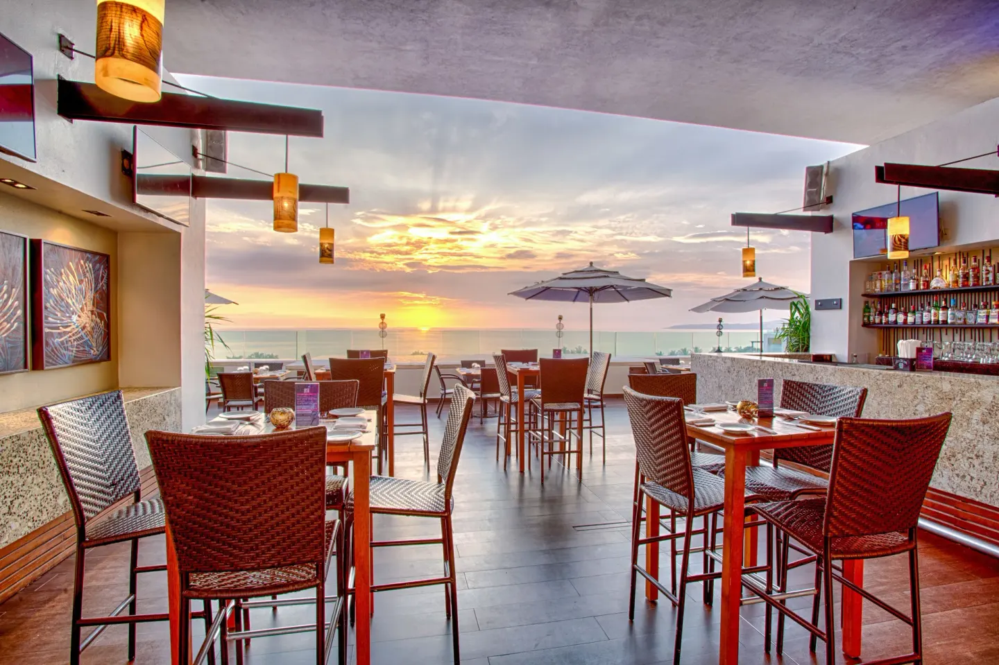 Rooftop bar and dining area facing the ocean at sunset at Marival Distinct World Spa.