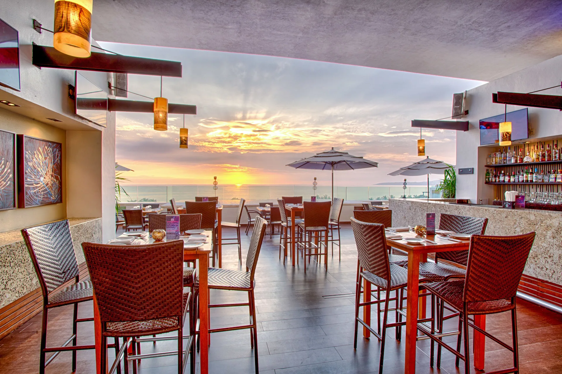 Rooftop bar and dining area facing the ocean at sunset at Marival Distinct World Spa.