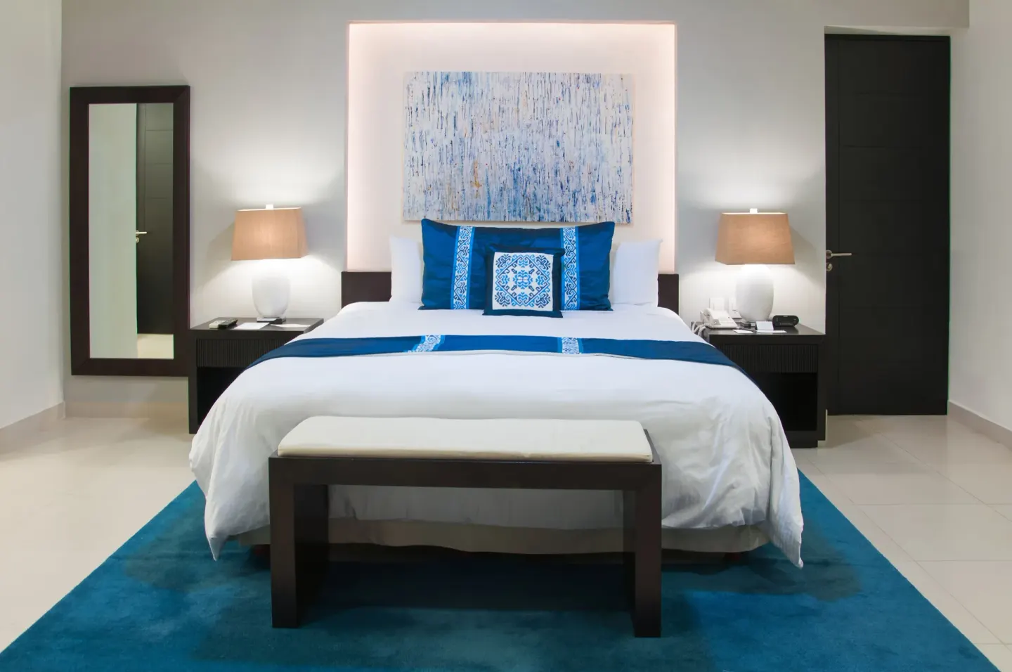 One-Bedroom Ocean View Suite king bed with blue accents at Marival Distinct World Spa.
