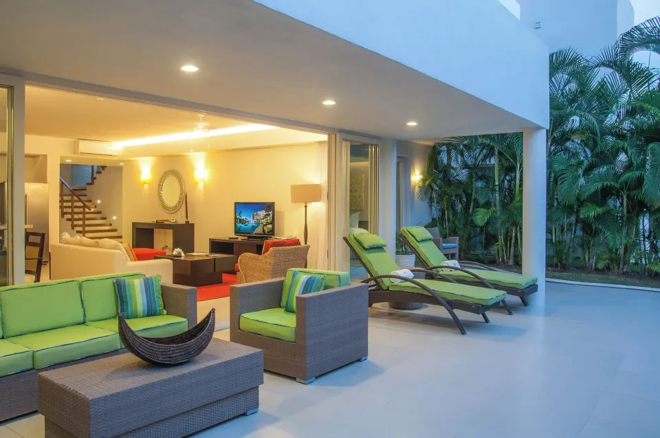 Three-Bedroom Villa covered patio with loungers and indoor living room at Marival Distinct World Spa.