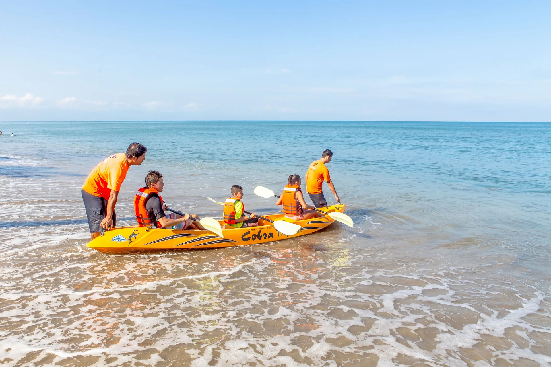 Guests launch a yellow kayak from the beach at Marival Emotions Resort.