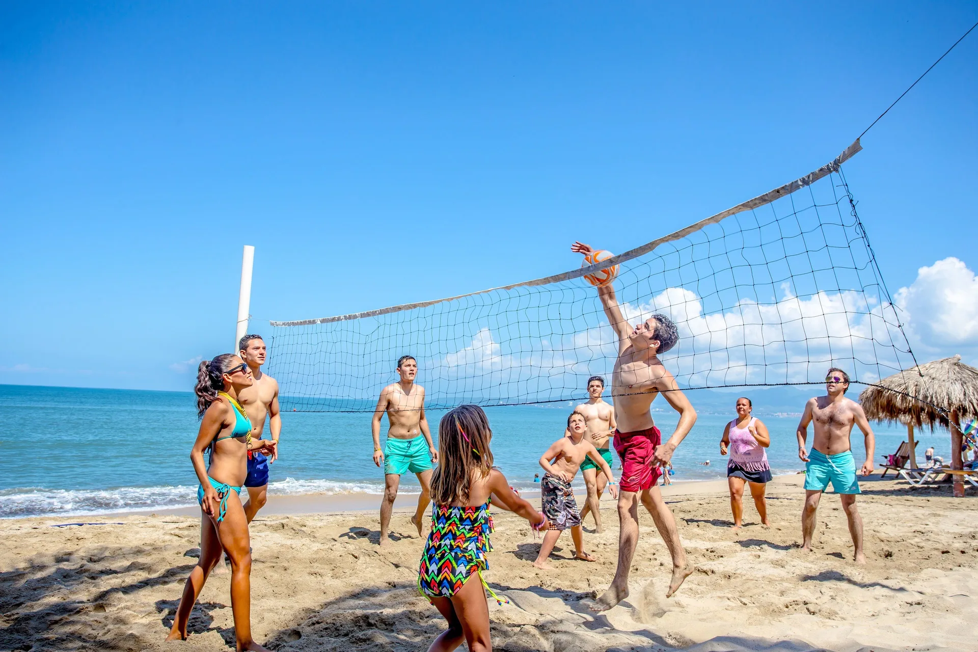 Guests playing beach volleyball by the ocean at Marival Emotions Resort.