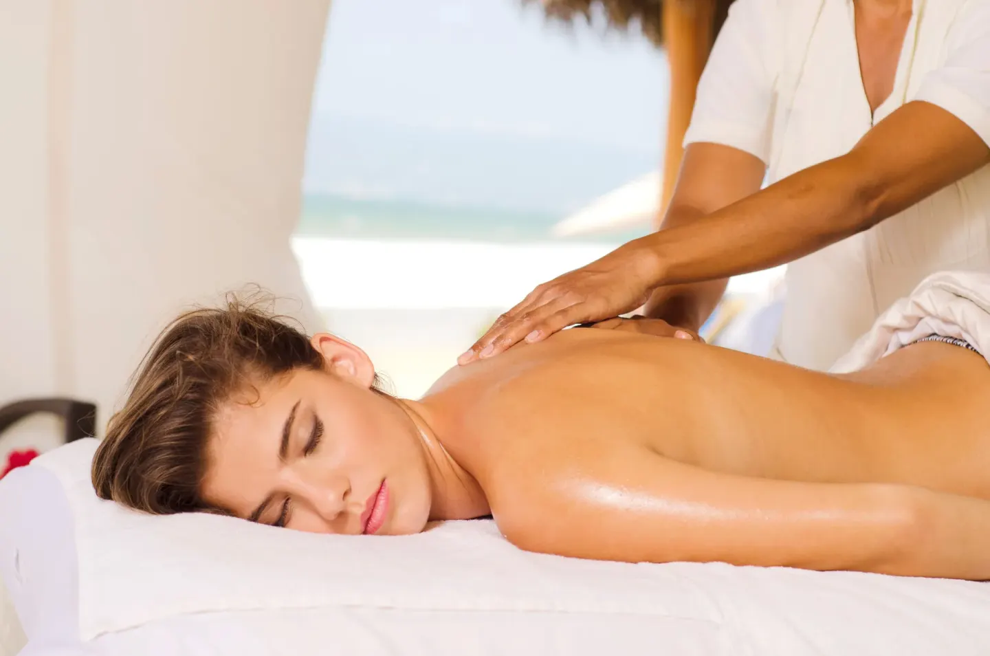 Guest receives an outdoor massage near the beach at Marival Emotions Resort.