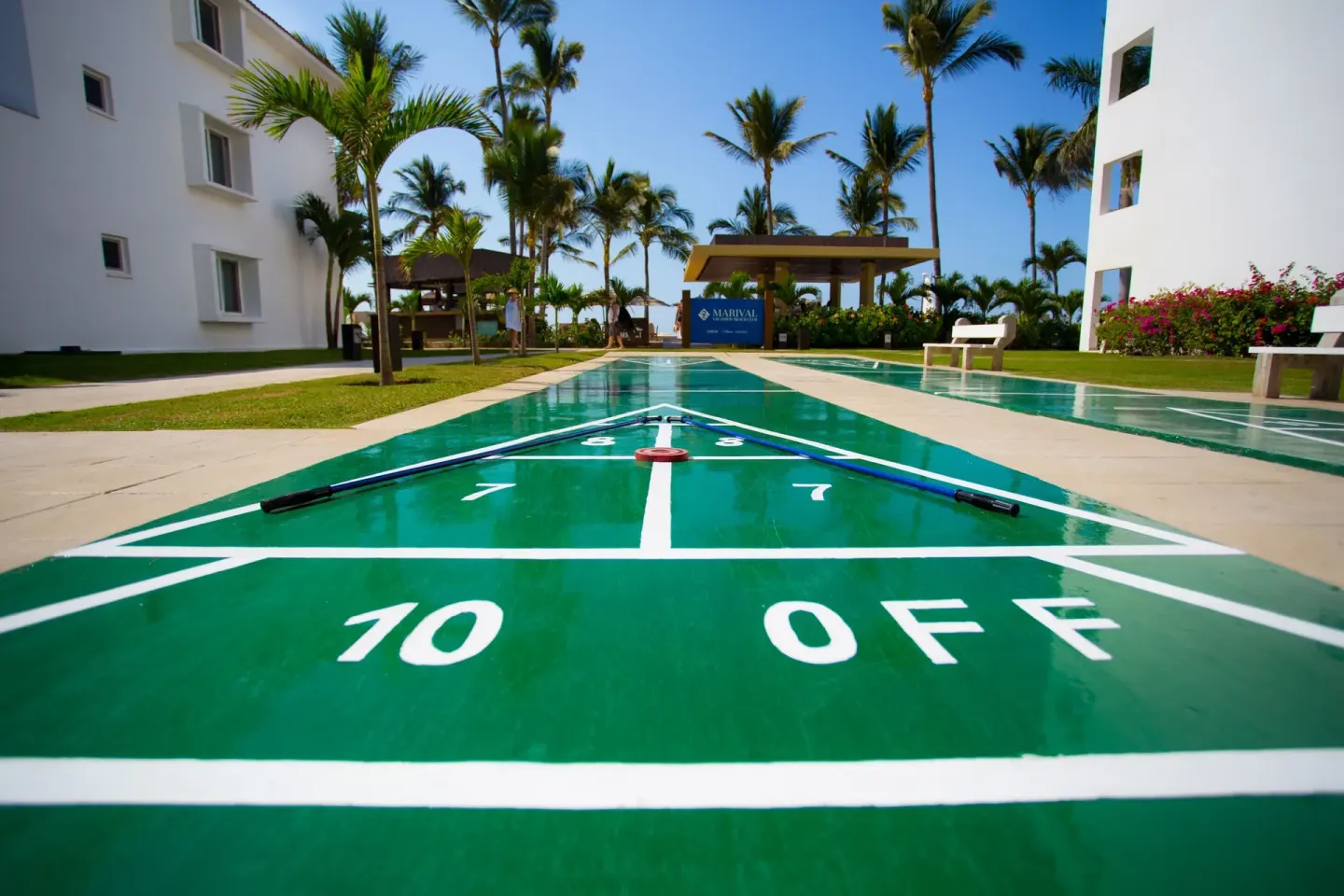 Green shuffleboard court with cues on the grounds at Marival Emotions Resort.