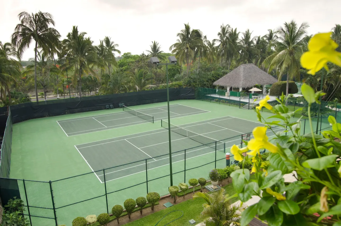 Tennis courts surrounded by palms and flowers at Marival Emotions Resort.