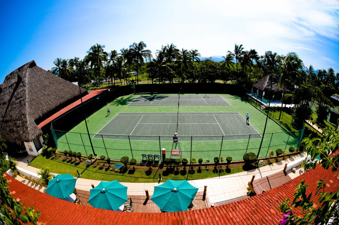 Aerial view of tennis courts surrounded by palms at Marival Emotions Resort.