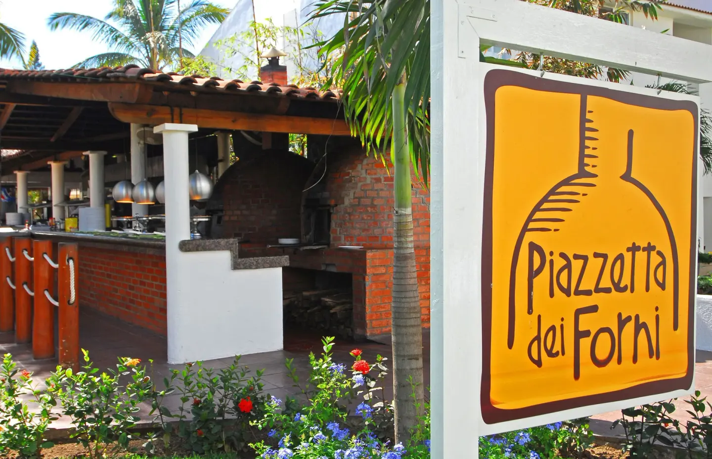 Piazzetta dei Forni sign beside an outdoor brick pizza oven at Marival Emotions Resort.