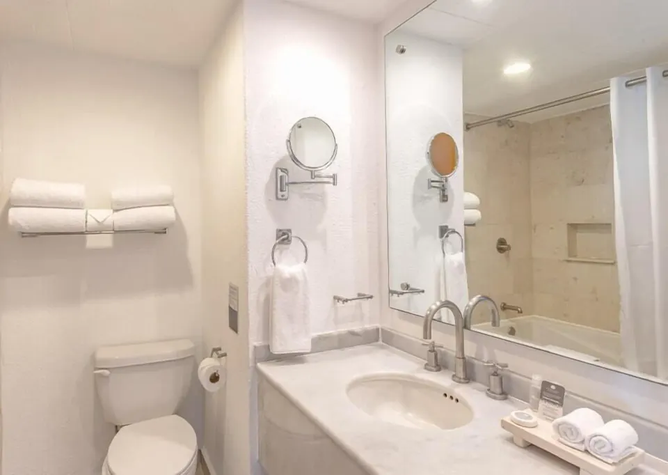 Club Room bathroom with sink, mirror, towels and tub at Marival Emotions Resort.