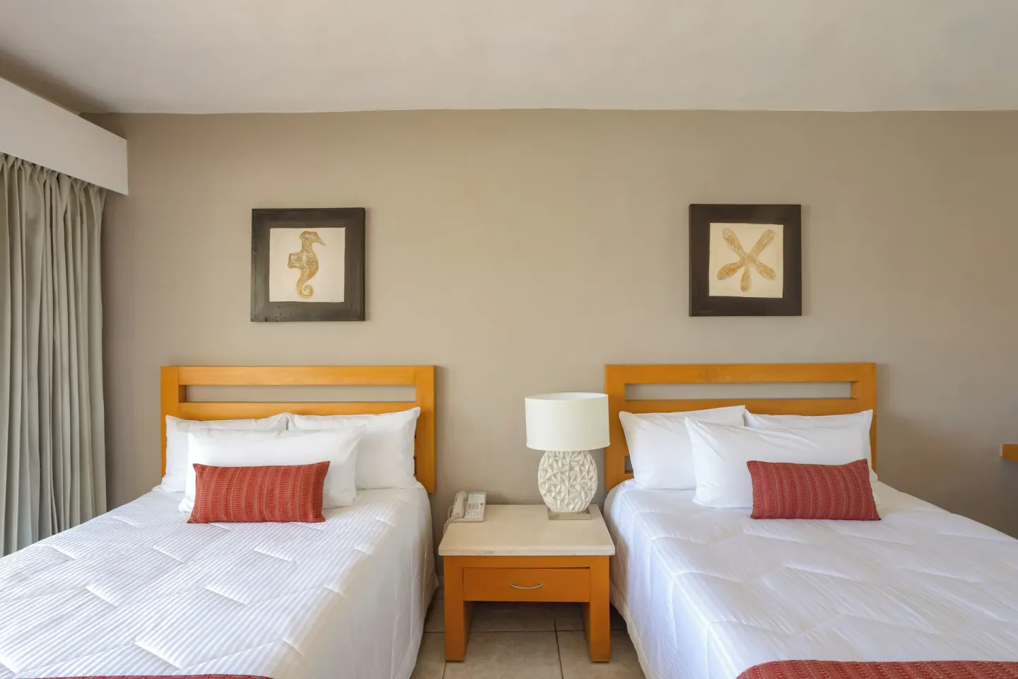 Two Club Room beds with bedside table and framed art at Marival Emotions Resort.