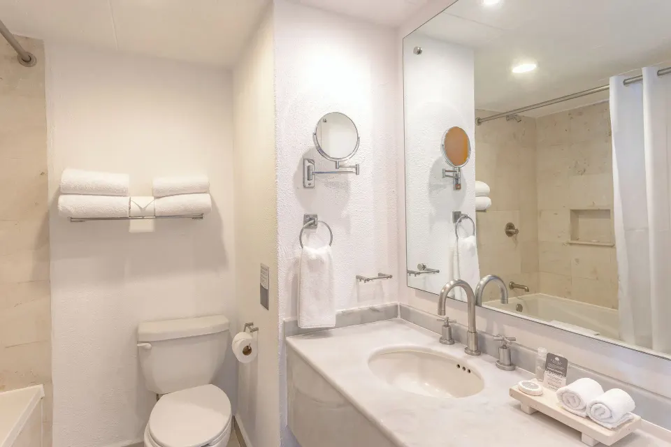 Grand Room bathroom with sink, mirror, toilet, tub, and towels at Marival Emotions Resort.