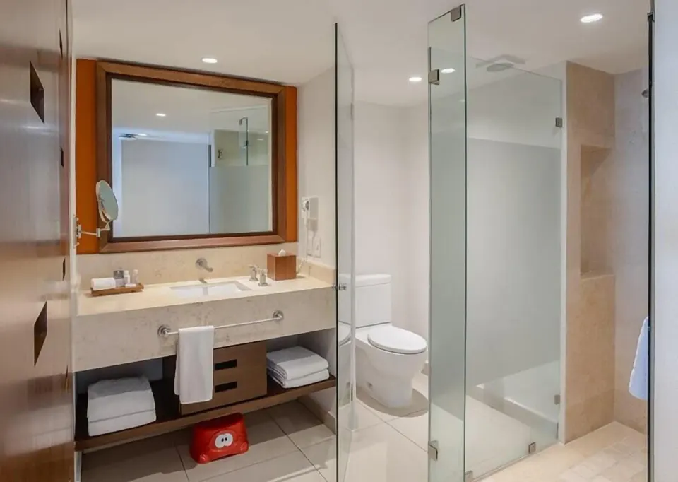 Grand Room bathroom with vanity, toilet, and glass shower at Marival Emotions Resort.