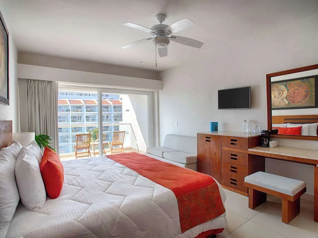 Grand Room with one bed, balcony seating, sofa, dresser, and TV at Marival Emotions Resort.