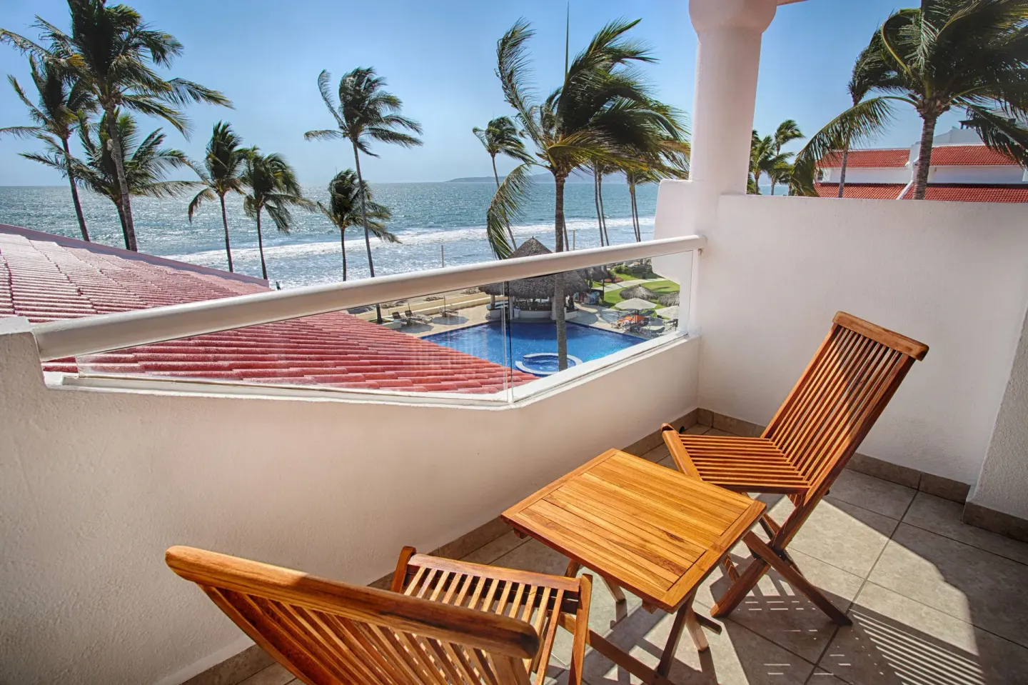 Oceanfront balcony with wood table and chairs at Marival Emotions Resort.