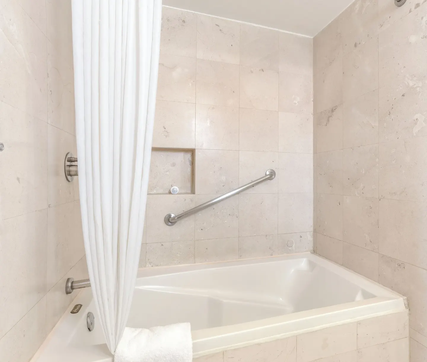 Bathroom tub with tiled walls and shower curtain at Marival Emotions Resort.