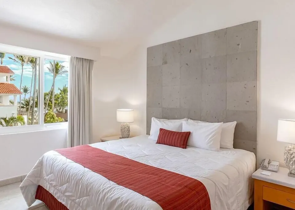 Oceanfront bedroom with king bed and window view at Marival Emotions Resort.