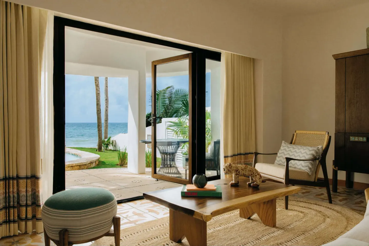Suite sitting area opening to a lawn, palms, and ocean at Maroma, Riviera Maya.