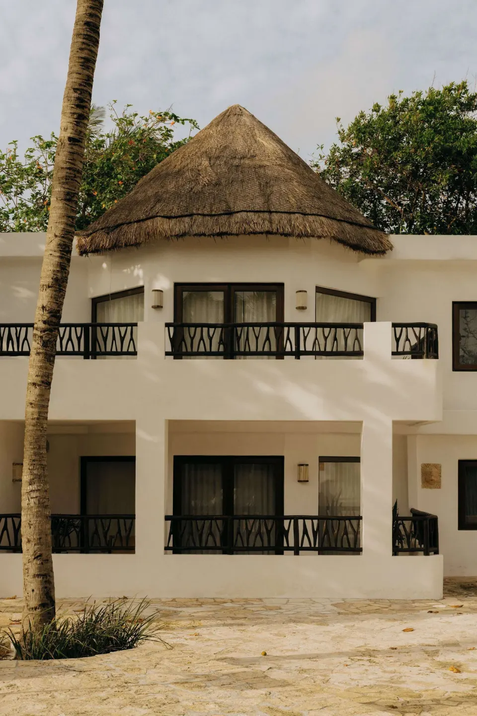 White guest building with balconies and a thatched roof at Maroma, Riviera Maya.