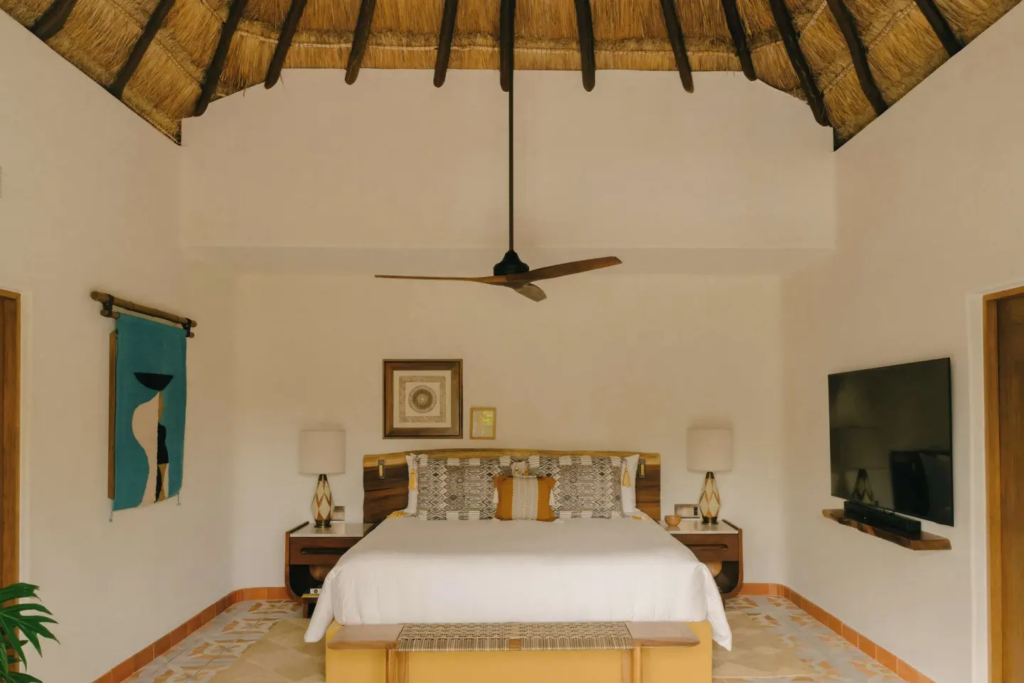 King bed beneath a thatched ceiling in a guest room at Maroma, Riviera Maya.