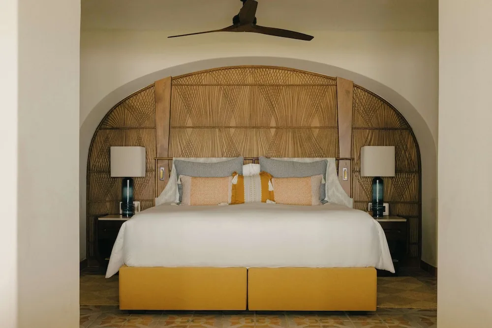King bed with woven arched headboard in a guest room at Maroma, Riviera Maya.