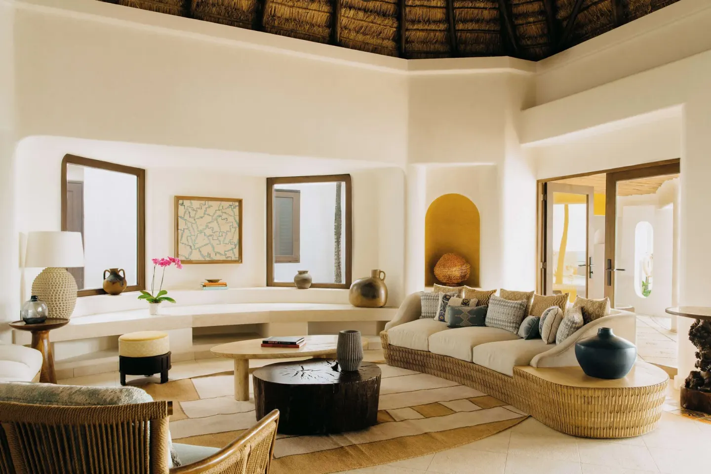 Cream lounge with wicker seating, round tables and thatched ceiling at Maroma, Riviera Maya.